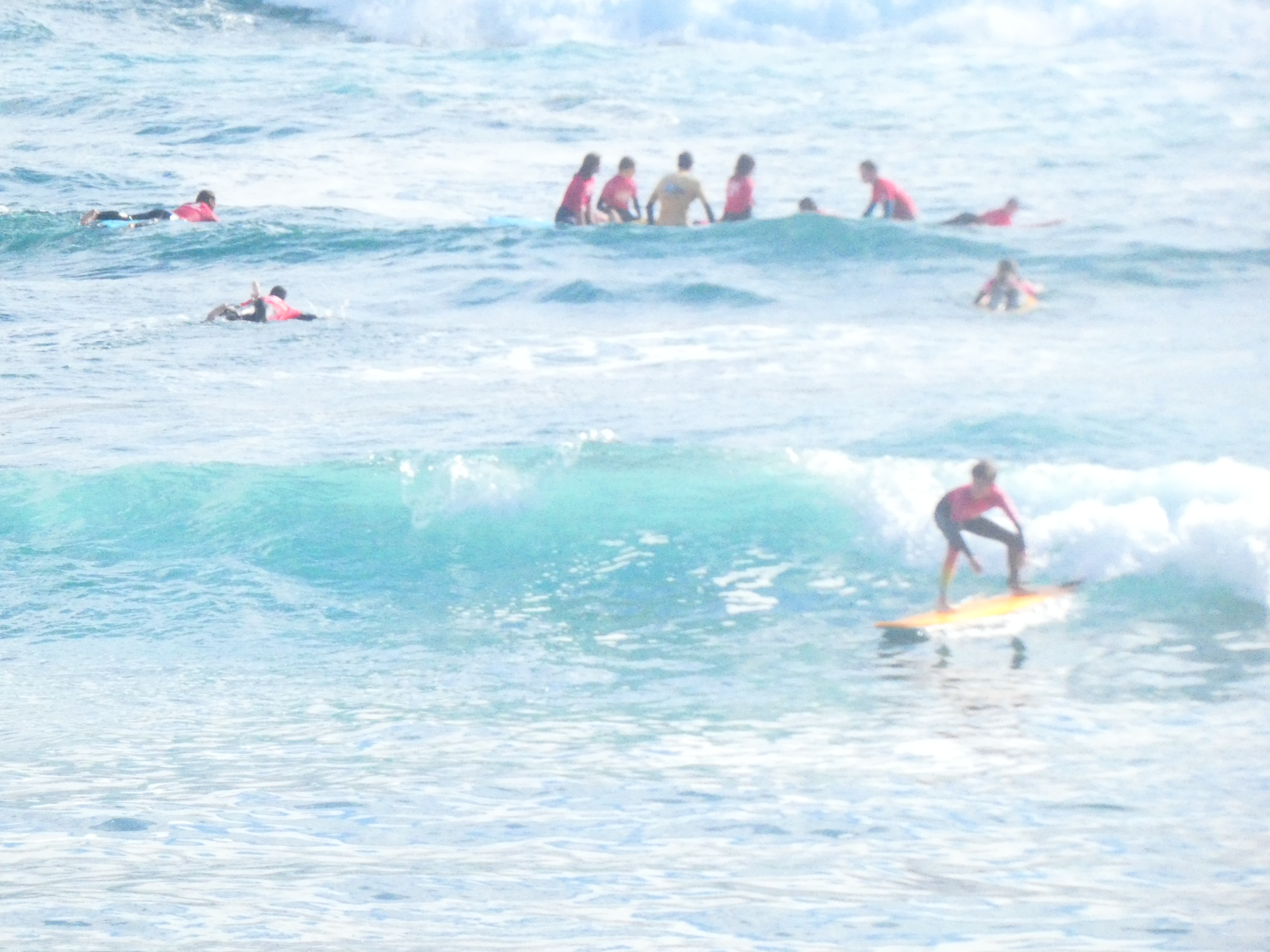 Alumnos en el mar surfando