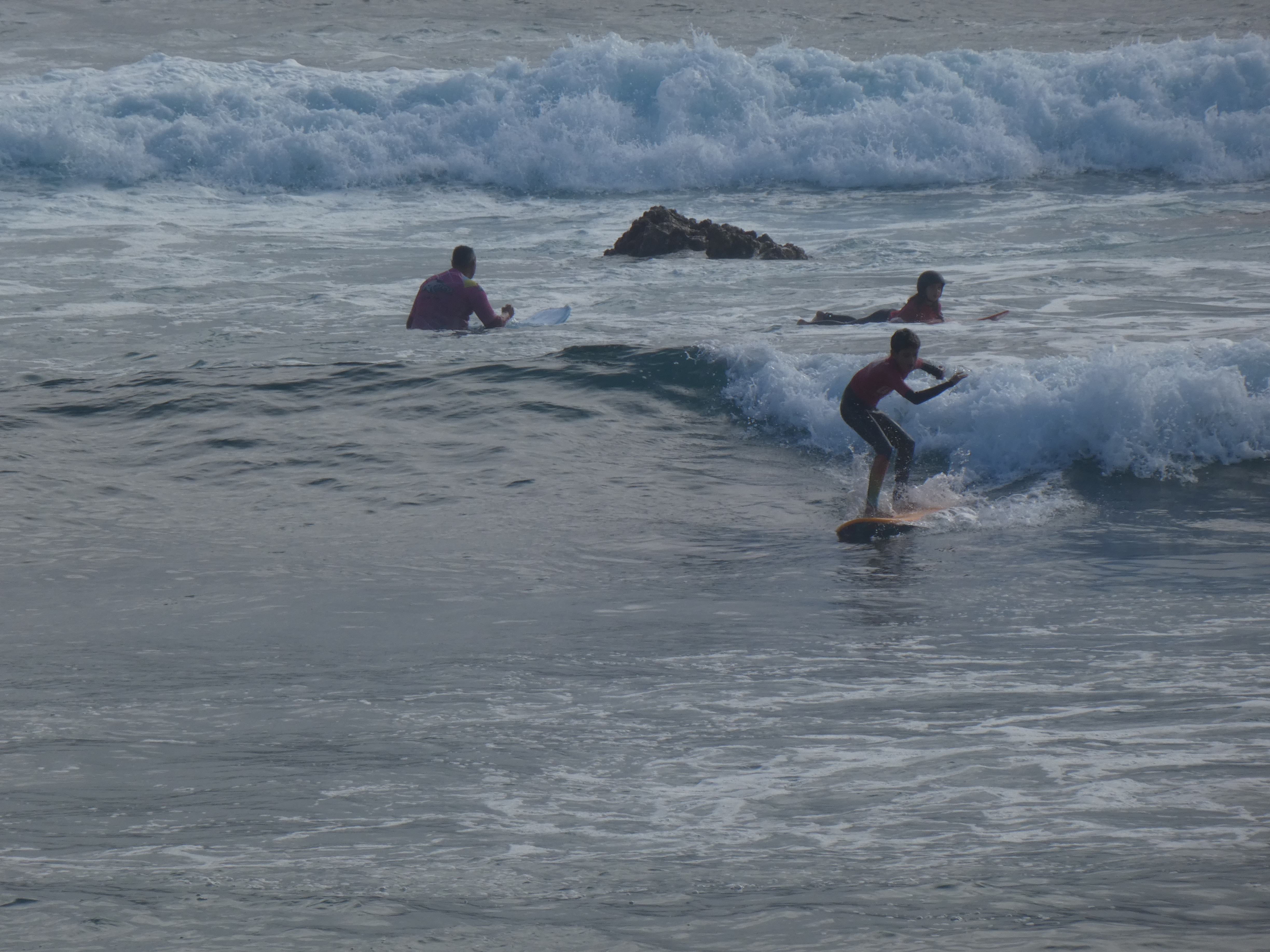 Alumnos en el mar surfando